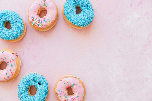 Overhead view of colorful donuts on pink backdrop