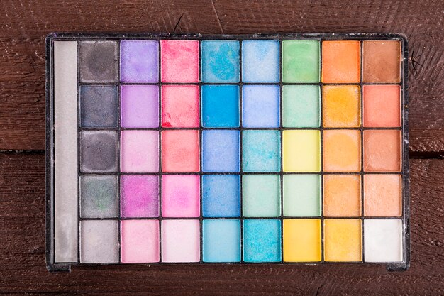 Overhead view of colorful eye shadow powder on wooden background