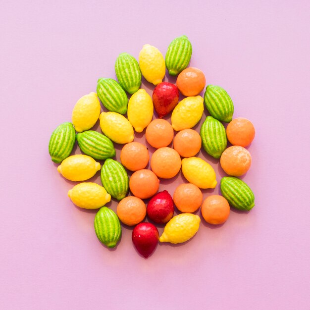 Вид сверху красочные конфеты фруктовой формы на розовом фоне