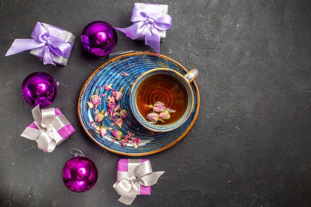 Overhead view of colorful gifts and decoration accessories a cup of black tea on dark background