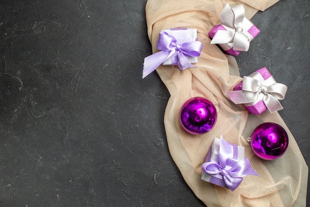 Overhead view of colorful gifts and decoration accessories for new year on nude color towel on black background