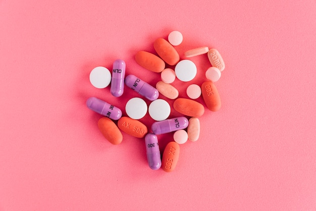 An overhead view of colorful pills on pink background