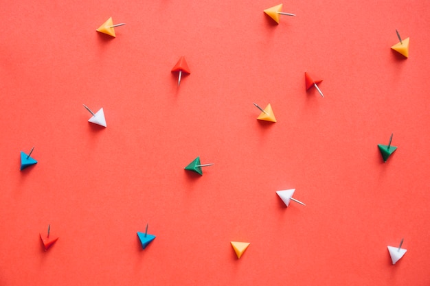 Overhead view of colorful triangular shaped push pins on orange background