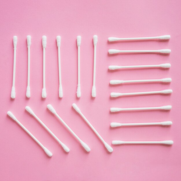 Overhead view of cotton swab arranged on pink background