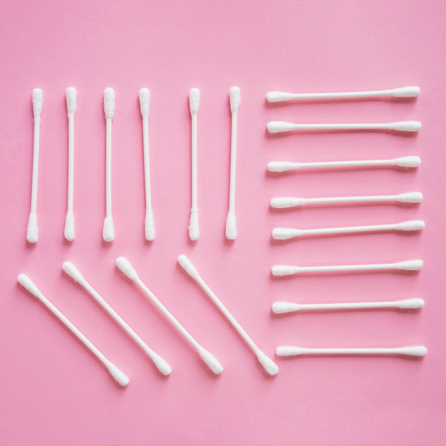 Overhead view of cotton swab arranged on pink background
