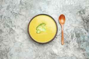 Free photo overhead view of creamy broccoli soup in a brown bowl and spoon on gray table