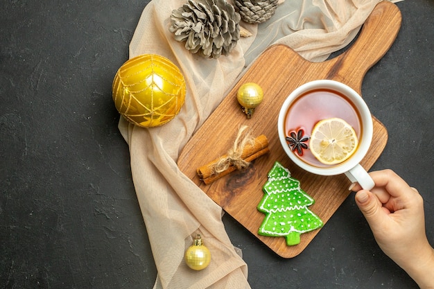 Overhead view of a cup of black tea with lemon and cinnamon limes new year decoration accessories on wooden cutting board