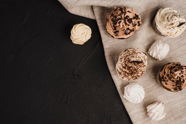 Overhead view of cupcakes and whipped creams on cloth