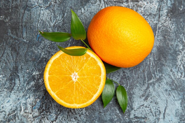 Overhead view of cut in half and whole fresh orange with leaves on gray background stock photo