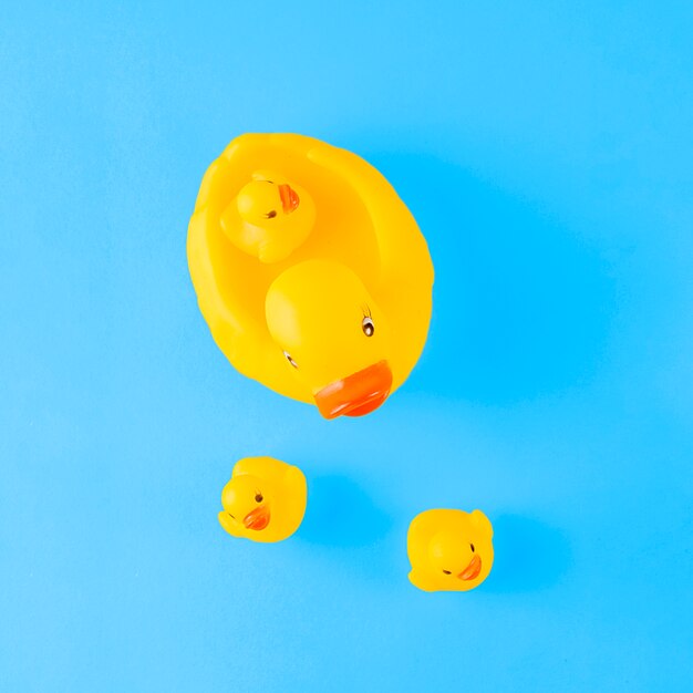An overhead view of cute yellow rubber duck with ducklings against blue background