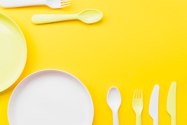 Free photo overhead view of cutlery; plates on yellow background