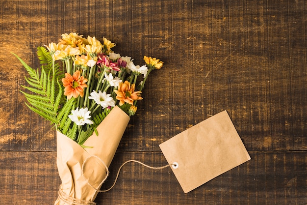 木の表面に繊細な花の束と茶色の紙タグのオーバーヘッドビュー