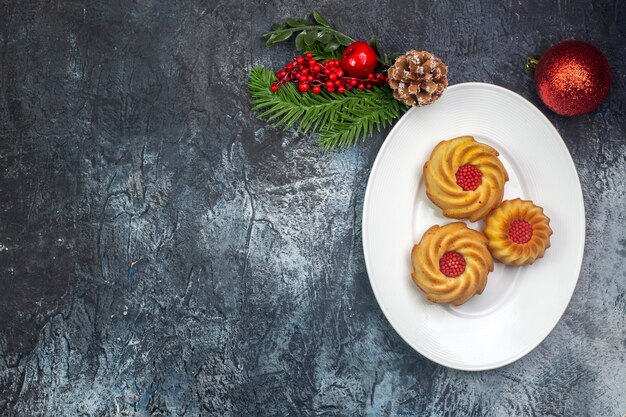 Overhead view of delicious biscuits on a white plate and new year decorations dark surface