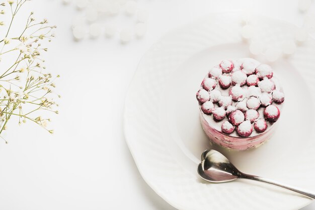 An overhead view of delicious cake with heart shape spoon on white plate against white backdrop