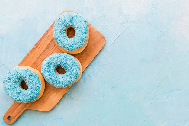 Free photo overhead view of delicious fresh donuts on wooden chopping board