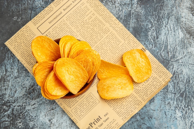 Overhead view of delicious homemade chips on newspaper on gray table