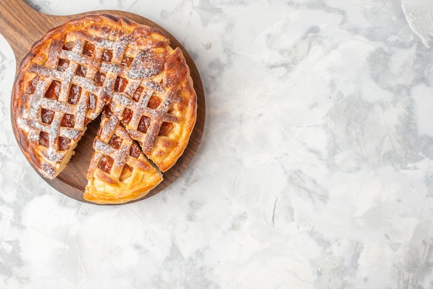 Free photo overhead view of delicious jam pie on a wooden cutting board on the right side on ice table with free space