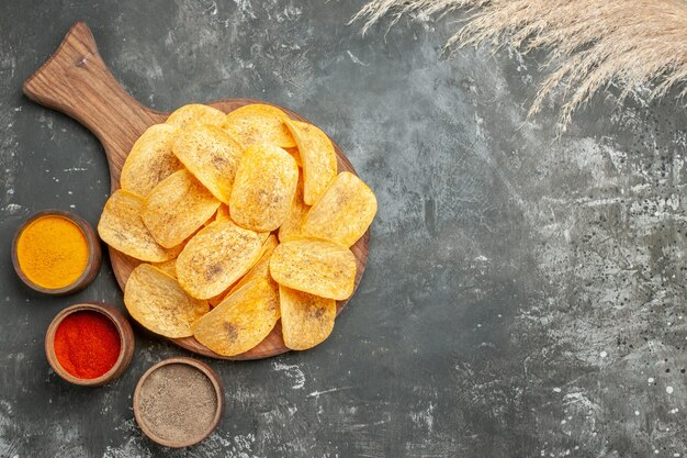 Overhead view of delicious potato chips spices with ketchup on gray table