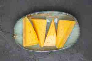 Free photo overhead view of delicious yellow sliced chees on a blue plate on black background