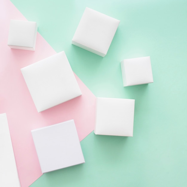 Overhead view of different white boxes on green and pink paper backdrop