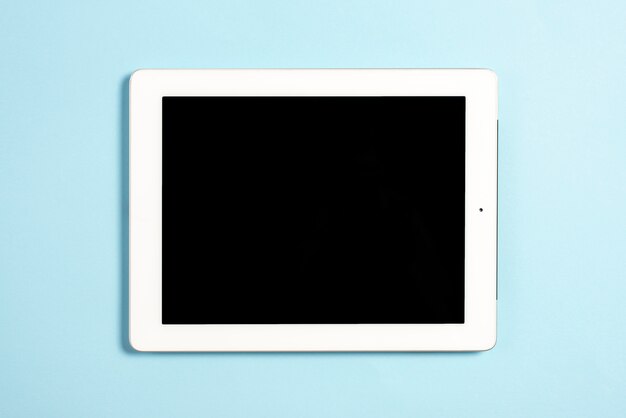 An overhead view of digital tablet with blank screen display on blue background