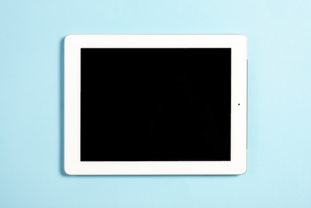 An overhead view of digital tablet with blank screen display on blue background