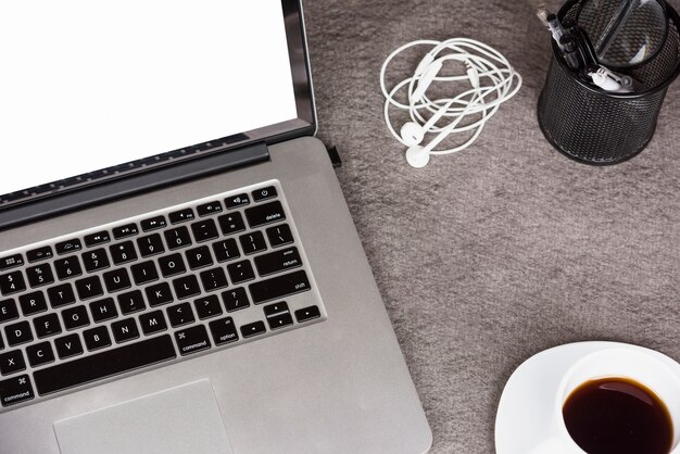 Вид сверху цифрового планшета с кофе; держатели для наушников и ручки на сером столе