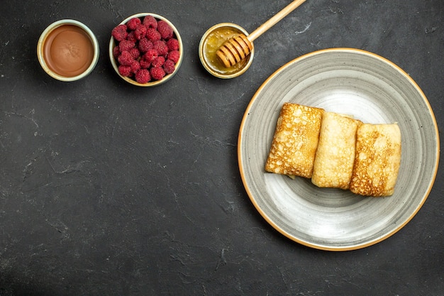 Overhead view of dinner background with delicious pancakes honey and chocolate raspberry on black background