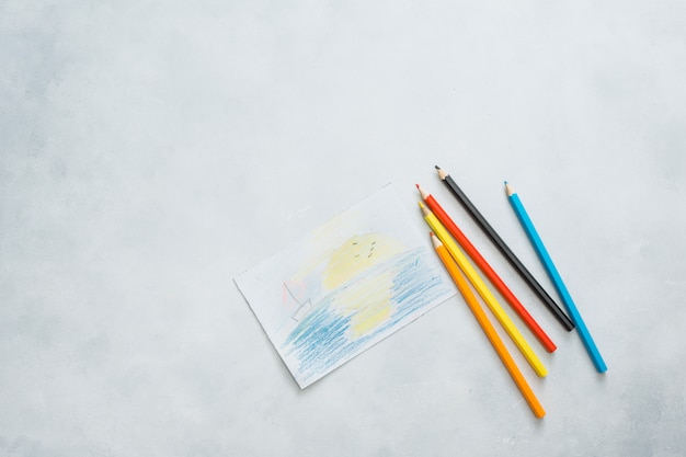 Free photo overhead view of drawn paper and color pencils on white background