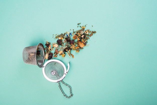 Free photo an overhead view of dried herbal tea with strainers on blue background