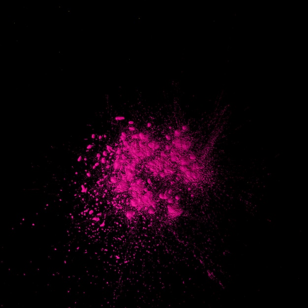 Overhead view of dry pink holi color above black backdrop