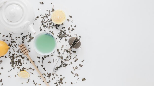 乾燥茶葉の俯瞰。茶こし;レモン;緑茶;蜂蜜ディッパーと白い背景の上のティーポット