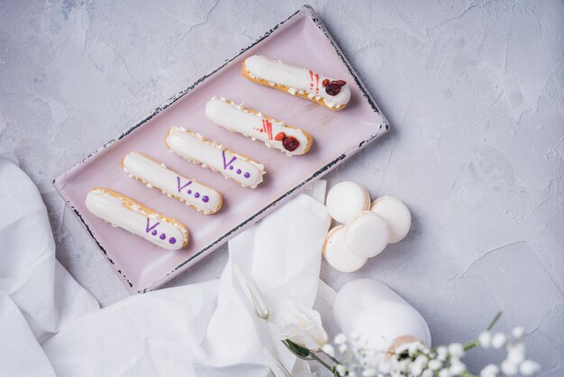 An overhead view of eclair tray with macaroons on textured backdrop