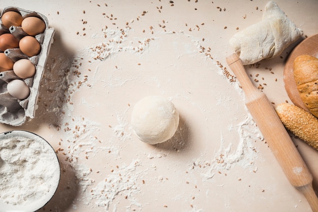 Overhead view of eggs; flour; dough and baked breads on background