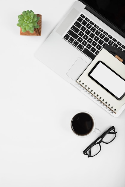 An overhead view of electronic portable device with coffee cup and eyeglasses