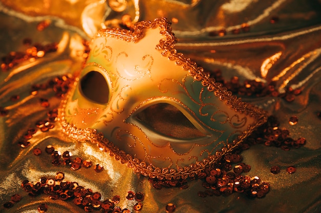 Una vista dall'alto di un'elegante maschera veneziana dorata su tessuto dorato con paillettes