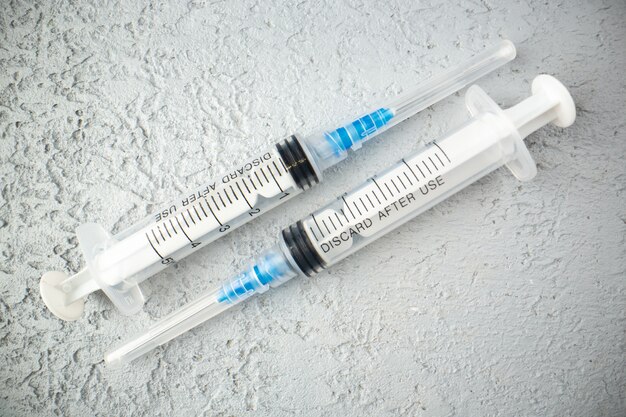 Overhead view of empty syringes on gray sand background with free space