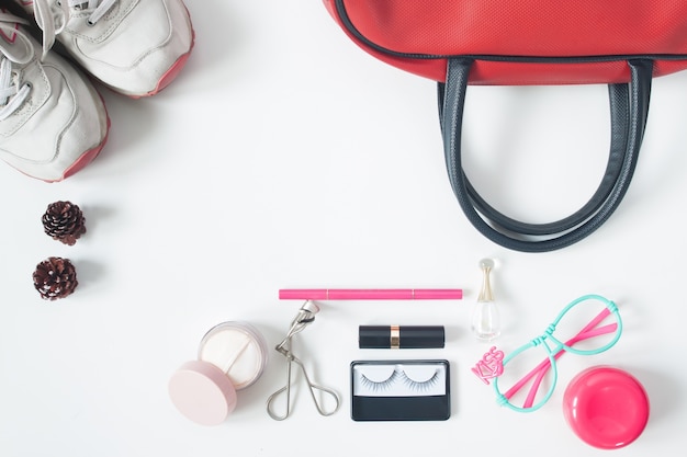 Free photo overhead view of essential beauty items, top view of red hand bag, fashion eyeglasses, cosmetics and sneakers, top view isolated on white background