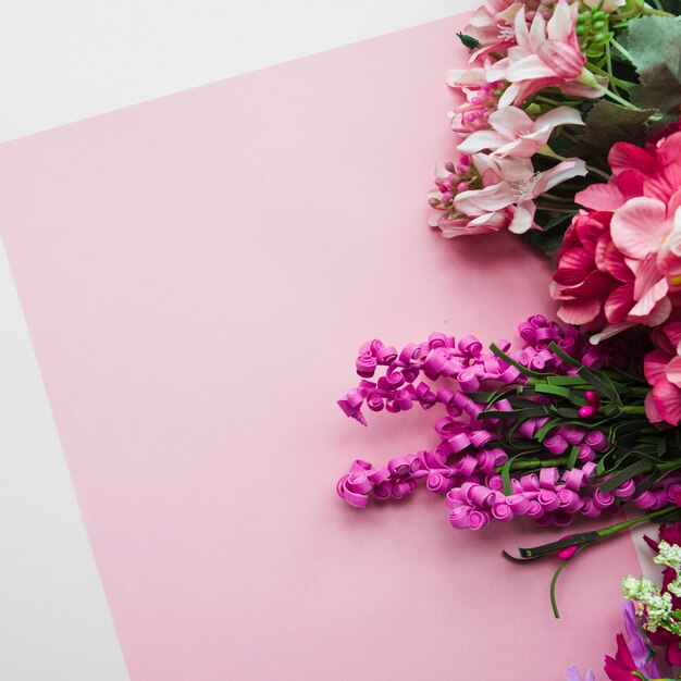 An overhead view of fake flowers on pink backdrop