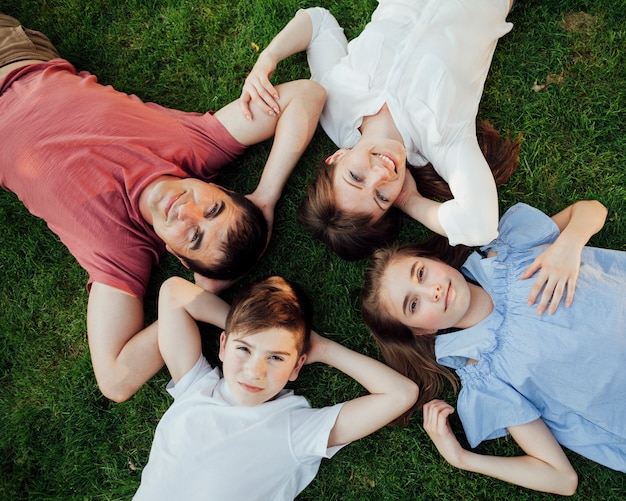 Overhead view of family lying on grass and looking at camera