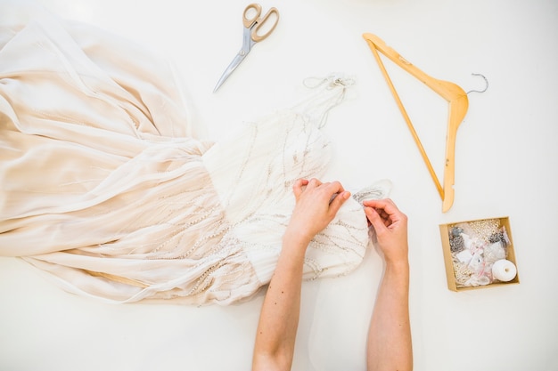 Overhead view of fashion designer's hand sewing dress