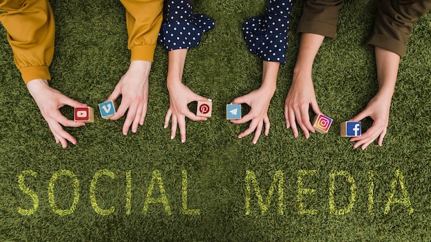 Overhead view of female's hand holding social network app symbol blocks on lawn