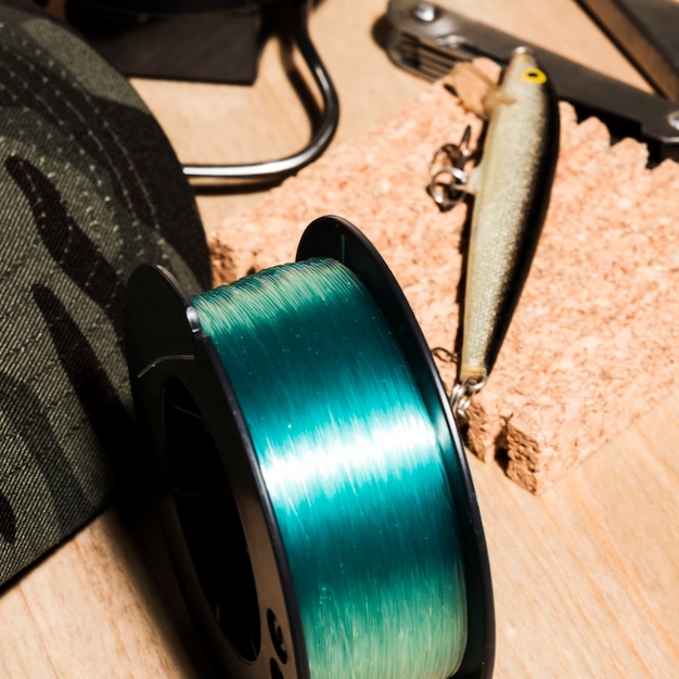 An overhead view of fishing reel and fishing baits on wooden surface