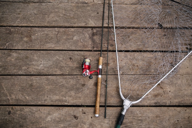 Free photo overhead view of fishing rod and net on wooden pier