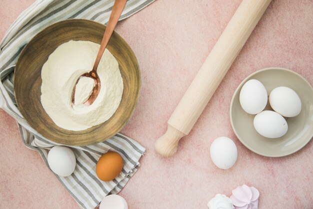 小麦粉の上から見た図。卵;麺棒と色付きの背景にナプキン