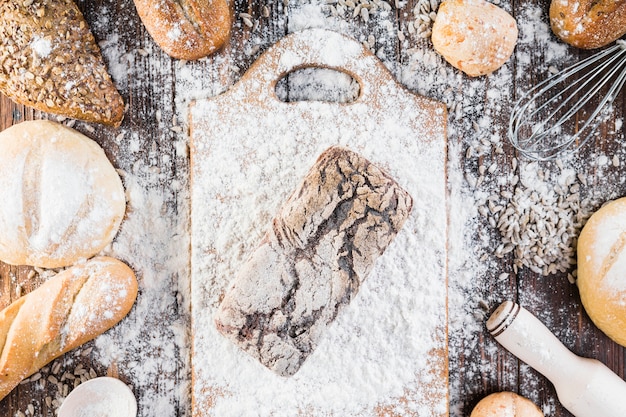 Foto gratuita vista dall'alto di farina sparsa sul pane cotto sul tavolo di legno