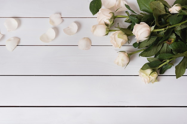 An overhead view of fresh beautiful white roses on wooden table