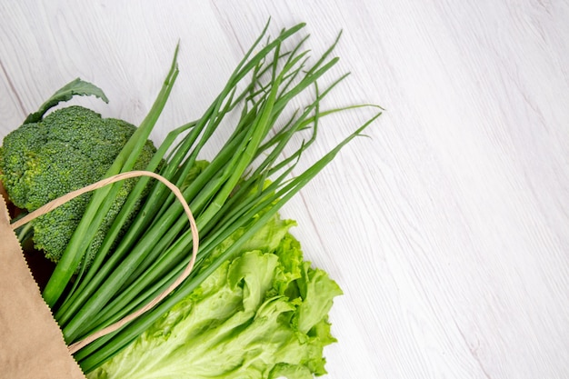 Overhead view of fresh broccoli in a brown basket on white table