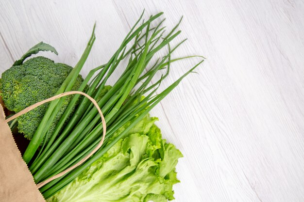 Overhead view of fresh broccoli in a brown basket on white table