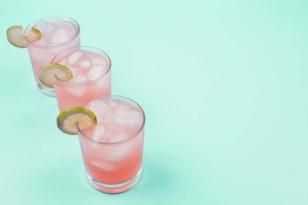 An overhead view of fresh cocktail with lemon slice and ice cubes on mint background